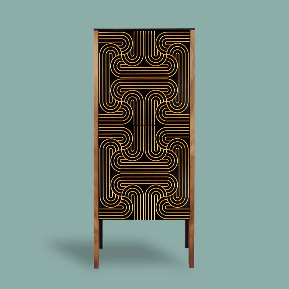 A tall, narrow cabinet or storage unit with a black front featuring a geometric gold line pattern, framed by warm brown wood sides and supported by slim legs, set against a solid muted teal background.