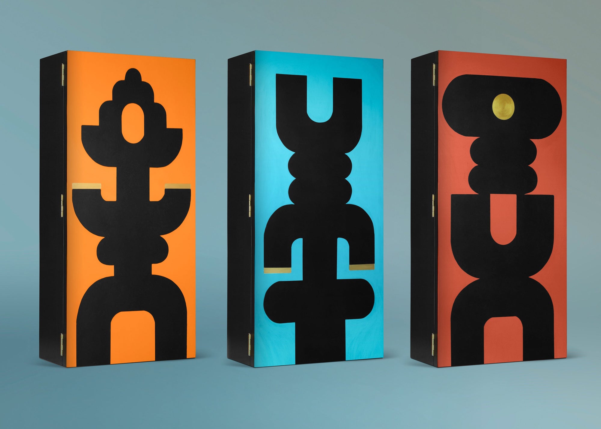 Three cabinets with geometrically shaped designs in black on an orange, turquoise or rust background.