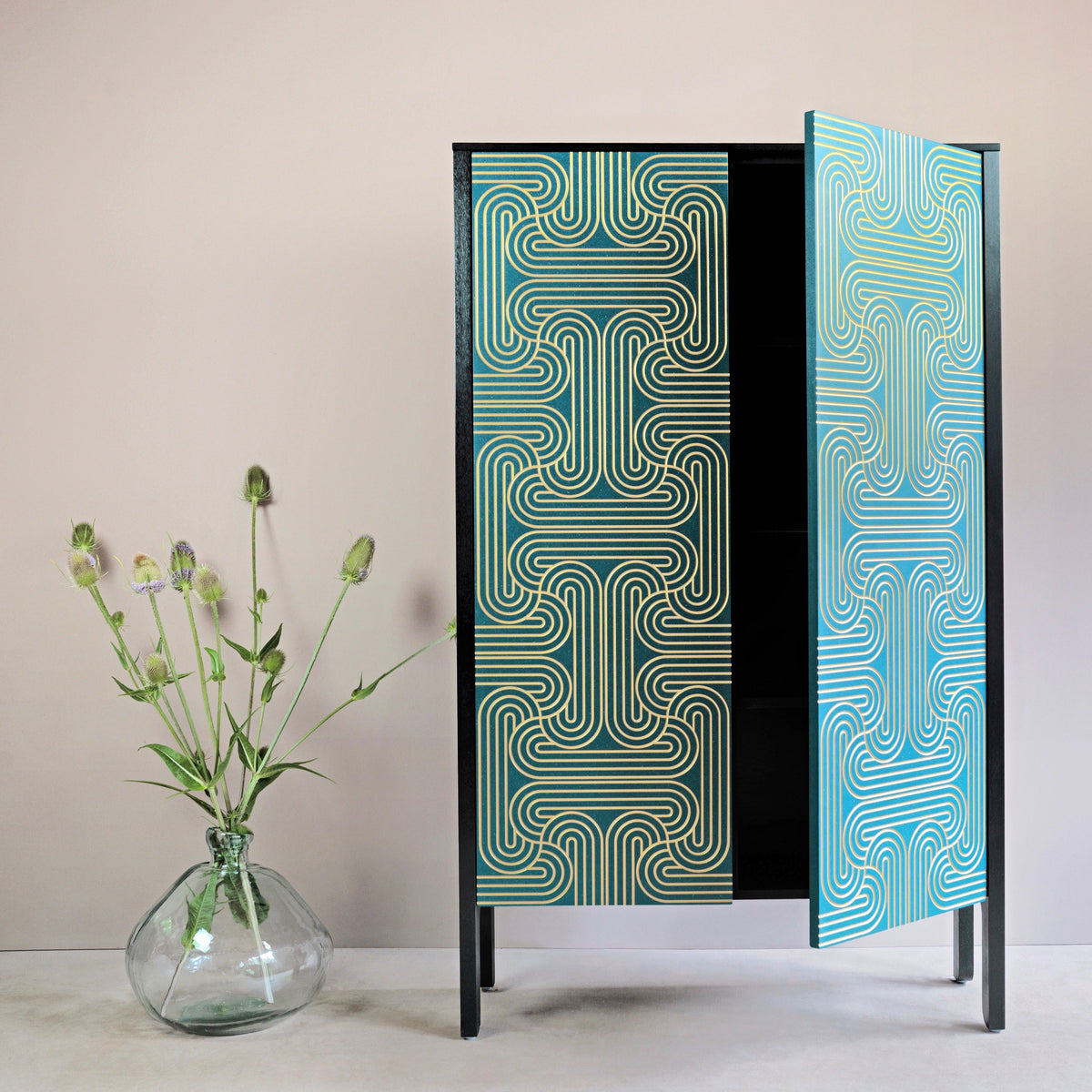 A Long door cabinet with handpainted loop pattern in gold on blue doors, with sides stained in black and a hard wax oil finish. 