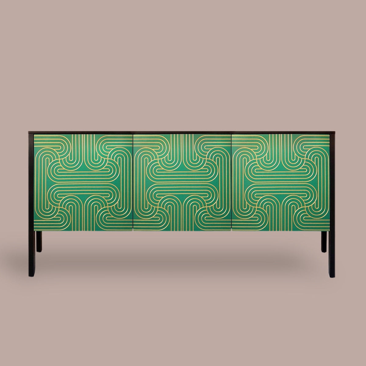 A modern sideboard or credenza with a green and gold geometric patterned front, supported by slim black legs, set against a solid taupe background.
